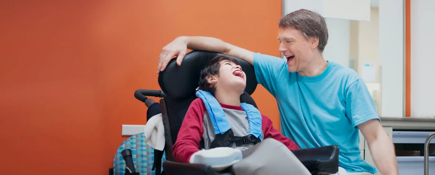 Ein lachendes Kind mit einem Elternteil während der Stammzell-Rehabilitation